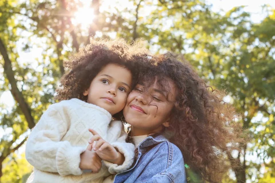 Mother and daughter hugging and smiling outdoors