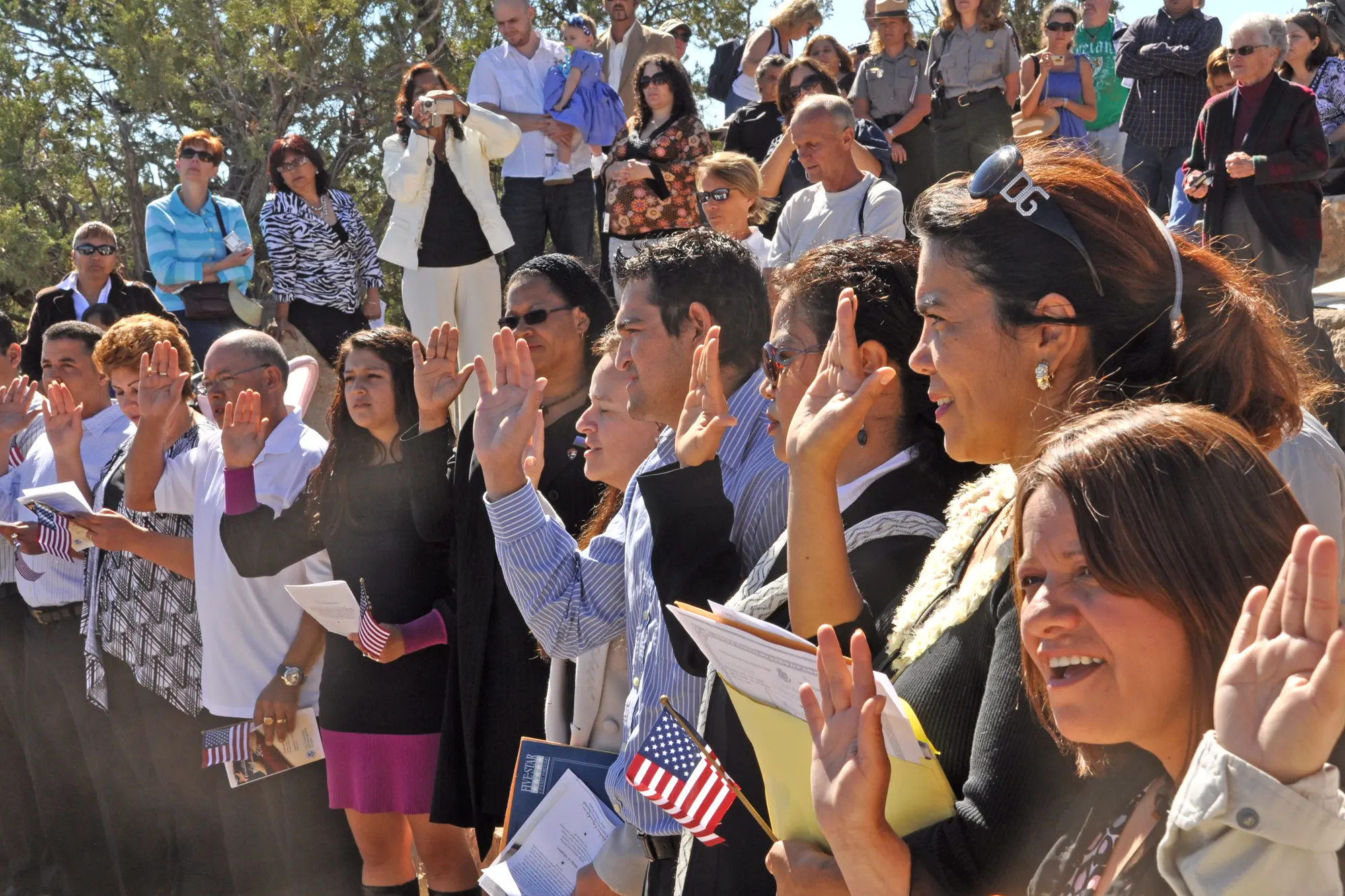 People raising their hands during a U.S. citizenship oath ceremony